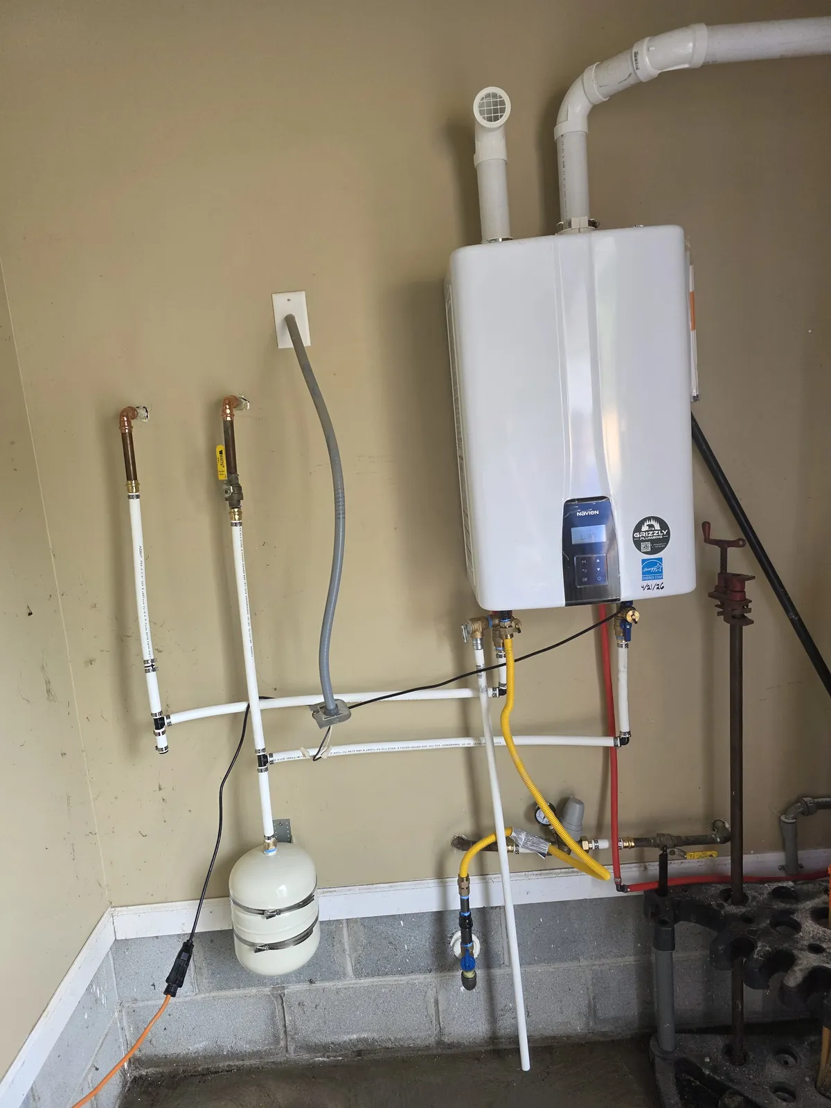 Navien tankless water heater installed in a basement by Grizzly Plumbing